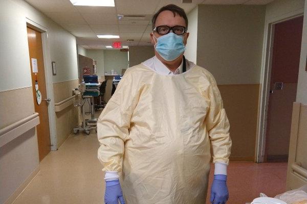 戴着口罩和手套的保罗·莱曼站在医院里.